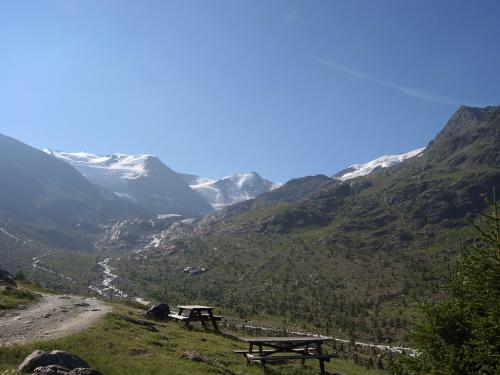 two picnic tables on a hill overlooking a mountain valley at Albergo Thurwieser in Santa Caterina Valfurva
