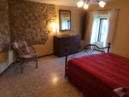 een slaapkamer met een rood bed en een stoel bij Casa Panoramica Pereta in Pereta