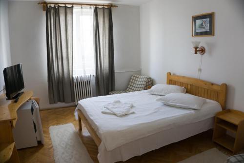 a bedroom with a white bed and a window at Hotel Merkur in Miercurea-Ciuc