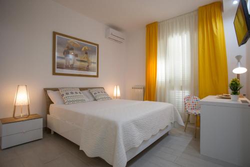 a bedroom with a white bed and yellow curtains at B&B Sapore di Sale con parcheggio ed ombrellone in spiaggia in Porto Cesareo