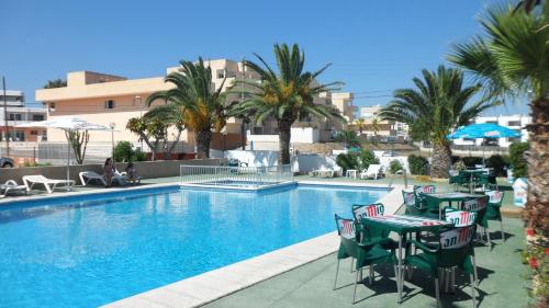 een zwembad met tafels en stoelen en palmbomen bij Apartamentos Alba in San Antonio Bay