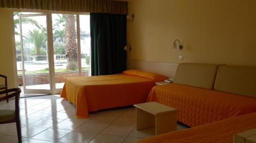Habitación con 2 camas, sofá y ventana en King's House Hotel Resort, en Mascali