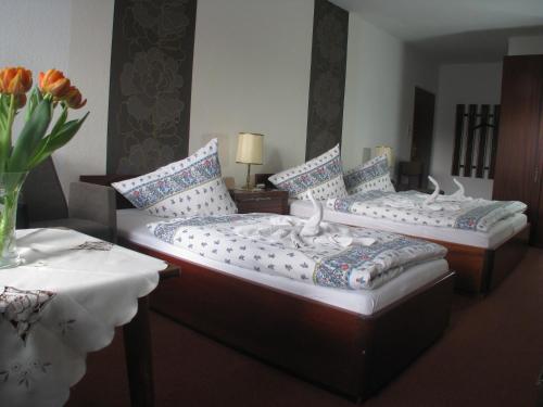 two beds in a room with a table and flowers at Hotel Am Kurpark in Malente
