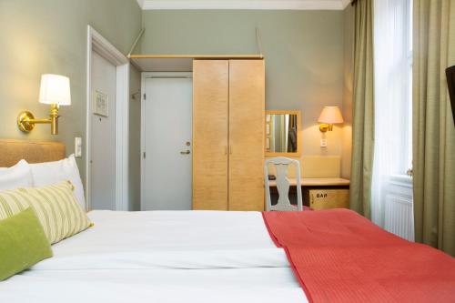 a bedroom with a white bed with a red blanket at Lady Hamilton Hotel in Stockholm