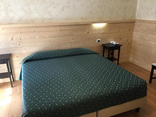 ein Schlafzimmer mit einem Bett mit einer grünen Bettdecke in der Unterkunft Al Garibaldino in Posina