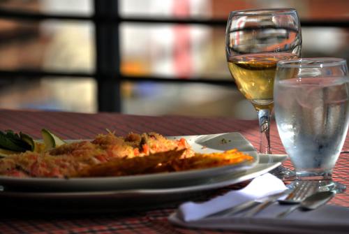 a plate of food and a glass of wine on a table at Hotel San José Plaza in Bucaramanga
