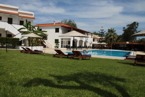 a group of chairs sitting in the grass next to a house at Vallian Village Hotel in Paradeísion
