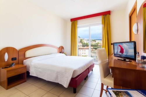 a hotel room with a bed and a desk and a television at Piccolo Hotel in Diano Marina