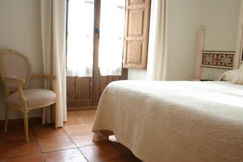 a bedroom with a bed and a chair and a window at Hostal Santa María de Úbeda in Úbeda