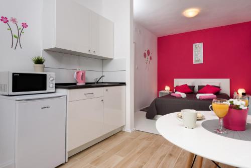 une cuisine et un salon avec un mur rose dans l'établissement Studio Apartment Gina, à Trogir