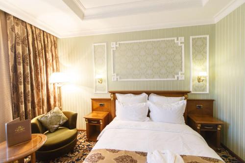 a hotel room with a bed and a chair at Sultan Palace Hotel in Atyrau