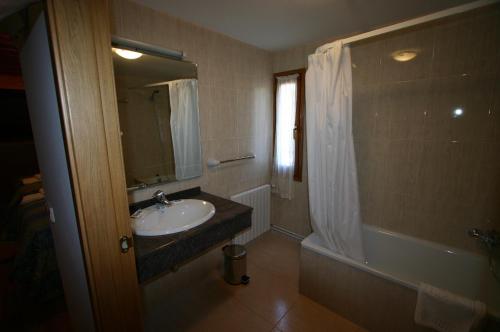 a bathroom with a sink and a tub and a mirror at Hotel Can Mestre in El Pont de Suert