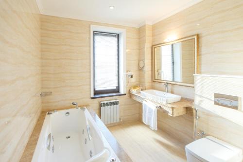 a bathroom with a tub and a sink and a toilet at Sultan Palace Hotel in Atyraū