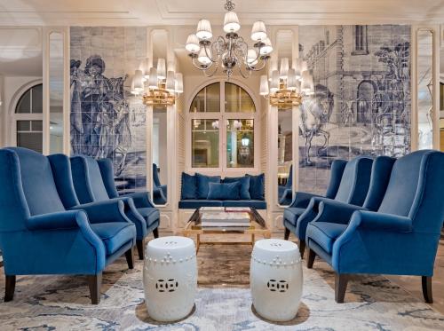 a living room with blue chairs and a chandelier at H10 Duque de Loule in Lisbon