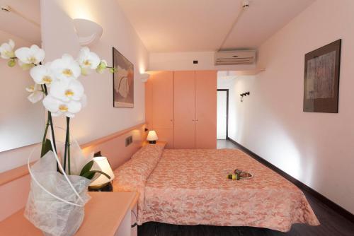 a room with a bed and a vase of flowers at Hotel Centrale in Riva del Garda
