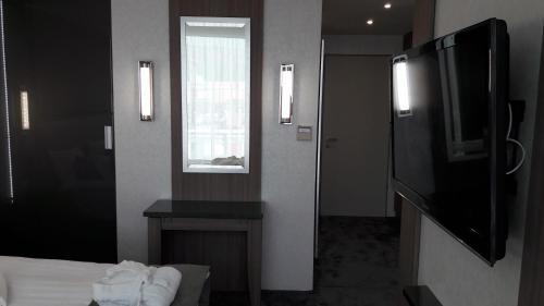 a room with a bed and a television and a window at Hotel Zena Beauty & Shopping Center in Hévíz