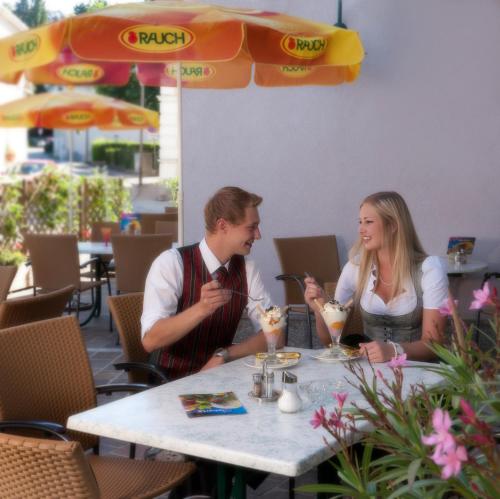 Ein Mann und eine Frau, die mit Getränken am Tisch sitzen. in der Unterkunft Hotel Hallerhof in Bad Hall