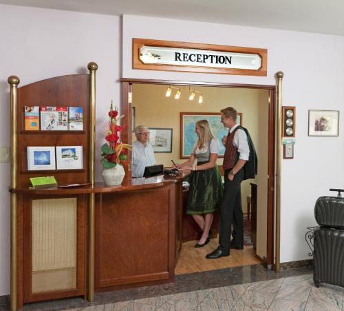 a man and a woman standing at a reception desk at Hotel Hallerhof in Bad Hall