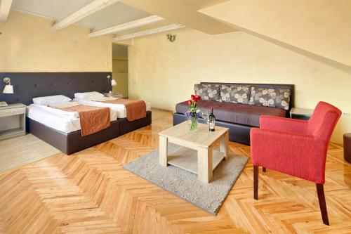 a hotel room with a bed and a red chair at Hotel Fontana in Novi Sad