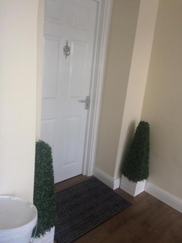 a hallway with a white door and two green plants at The Oxfordshire in Blackpool