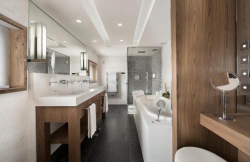 a bathroom with two sinks and a tub and a toilet at Hôtel Barrière Les Neiges Courchevel in Courchevel