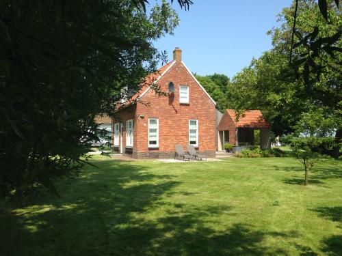 a red brick house with a bench in a yard at Dijkhuis Breskens in Breskens