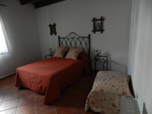 a bedroom with a bed with a red blanket at Alojamiento Rural La Rabida 25 in Cumbres Mayores
