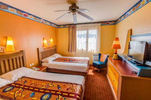 a bedroom with two beds and a flat screen tv at Disney Hotel Santa Fe in Coupvray