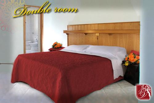 a bedroom with a large bed with a red blanket at Villa Verdiana in Nettuno