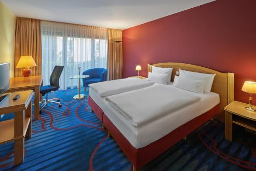 a hotel room with a bed and a desk at Mercure Hotel Berlin Tempelhof in Berlin