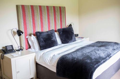 a bedroom with a bed with a black blanket on it at Milsoms Kesgrave Hall in Ipswich
