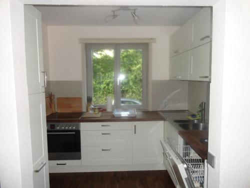 una cocina con armarios blancos y una ventana en Holzhaus mit grüner Aussicht zum Erholen en Burgheim