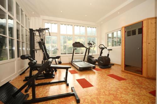 a gym with treadmills and ellipticals in a room with windows at Alpenhotel Neuwirt in Schladming