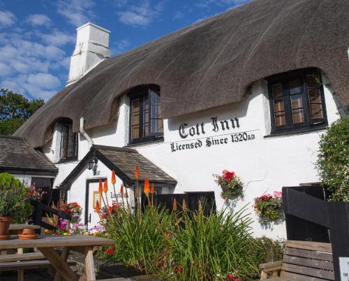 a building with a thatch roof with flowers on it at The Cott Inn in Totnes