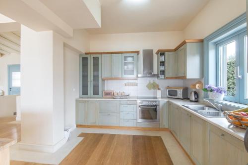 a large kitchen with white cabinets and a window at Villa Diamond in Porto Heli