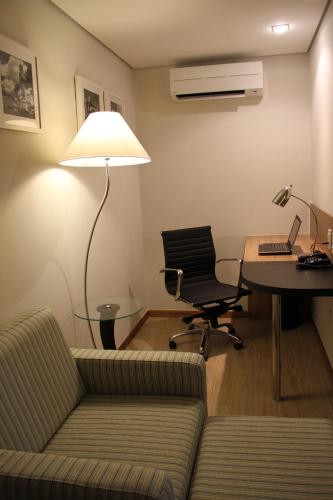 a living room with a couch and a desk and a lamp at Radisson Hotel Belém in Belém