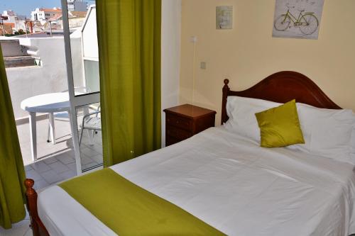 a bedroom with a bed with a green curtain and a balcony at Residencial A Doca in Faro