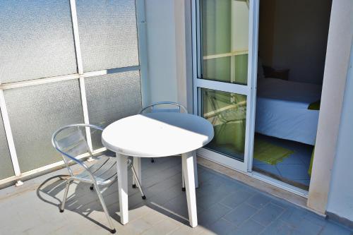 a small white table and a chair on a balcony at Residencial A Doca in Faro