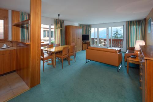 eine Küche und ein Esszimmer mit einem Tisch und Stühlen in der Unterkunft Aparthotel Helvetia in Crans-Montana