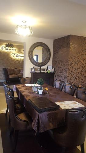 a dining room table with leather chairs and a mirror at Pensiunea Ellemar in Vatra Dornei