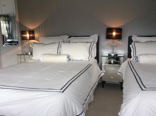 Glen na Smole في ويكلو: غرفة نوم بسريرين بها شراشف بيضاء ومصابيح