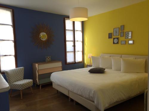 a bedroom with a large bed and a chair at Ancienne Cure in Buis-les-Baronnies