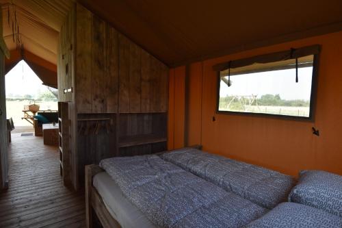 a bedroom with a bed and a window at Glamping Aan de Vleterbeke in Oostvleteren