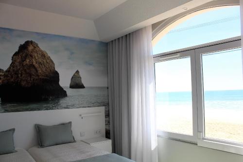 a bedroom with a bed and a large window at Golden Beach Guest House & Rooftop Bar in Faro