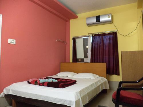 a bedroom with a bed with a red wall at Hotel Cosy Inn in Digha