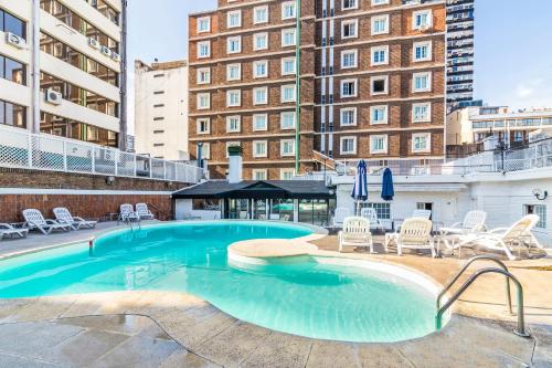 a swimming pool with chairs and tables and buildings at Claridge Hotel in Buenos Aires