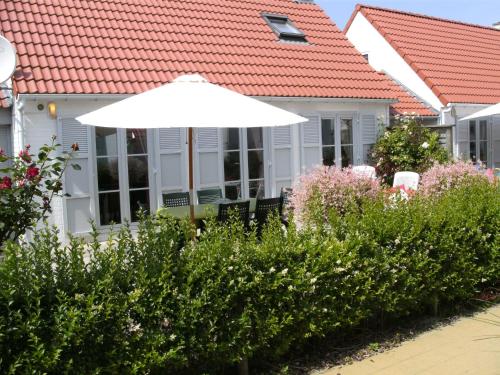 a white house with an umbrella and some bushes at Pleasant Holiday Home in De Haan by the Sea in De Haan