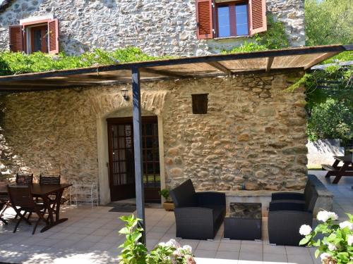 a patio with chairs and a table in front of a stone building at Beautiful holiday home near Moriani Plage in San-Nicolao