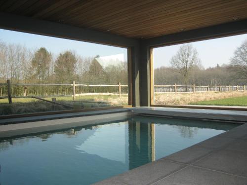 a swimming pool in a house with a view of a fence at Rural holiday home in former stables in Beernem