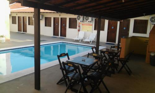 a swimming pool with tables and chairs next to a table and a pool at Hotel Sambaquis in São Luís
